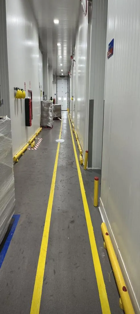Pasillo de planta con demarcación de piso en línea doble amarilla